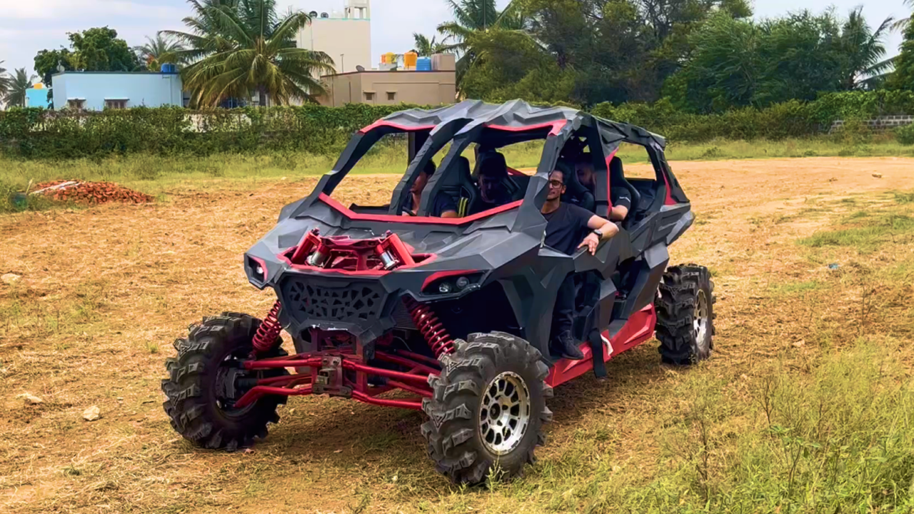 A red and black Arav, 4 seater, 4x4 off road vehicle positioned on rough ground, highlighting its robust features on terrains.