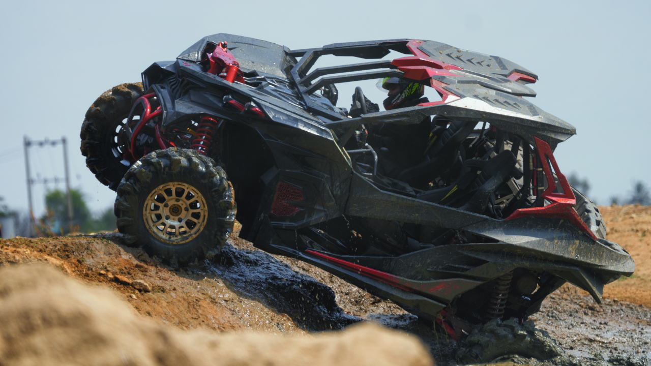 Ashva 4x4 red and black side by side vehicle, navigating through stones, slushy terrains showcasing its durable design and high performance on terrains.